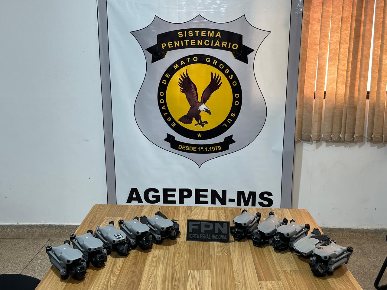 Drones expostos em mesa com o simbolo da Agepen ao fundo.